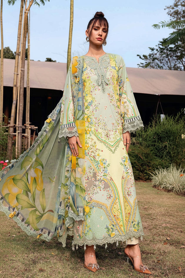 A fashion catalog page showing a model wearing a printed ethnic three-piece outfit with a long kurta, printed cambric trouser, and printed volkle dupatta. The outfit has a light yellow base with green and blue floral prints.