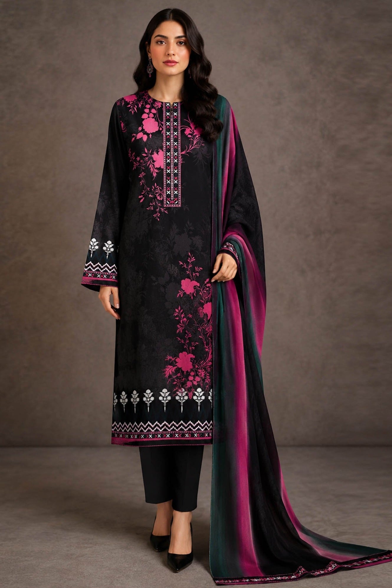 A promotional catalog image for a women's three-piece ethnic suit set from Design Stock, featuring a black kurta with pink floral embroidery and white geometric borders, a matching black chiffon dupatta with a pink border, and a black flat trouser. The image includes a full-body model shot on the left, a close-up portrait on the right, and product details and pricing on the right-hand panel.