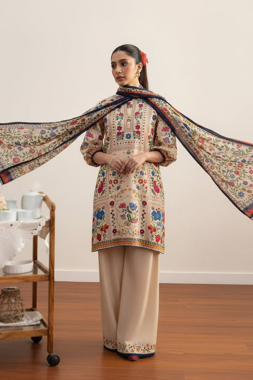 A model wearing a beige printed lawn shirt and trouser set from Coco by Zara Shahahan, shown in a lifestyle presentation with product details and care instructions printed on the right side of the white background.