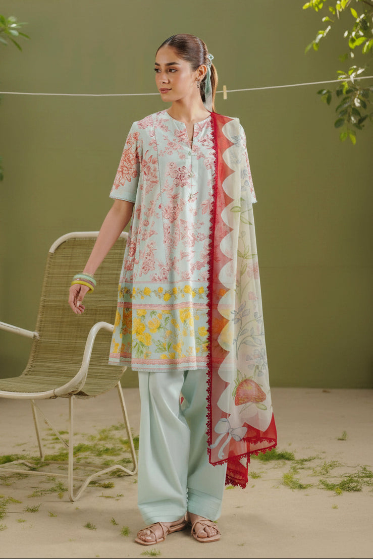 A promotional catalog page for COCO by Zara Shahjahan Prints, showing a woman modeling an ELVO-4B three-piece salwar suit. The left side features a blurred model wearing a light pink and yellow floral printed kurta, light blue pants, and a red and yellow patterned dupatta.