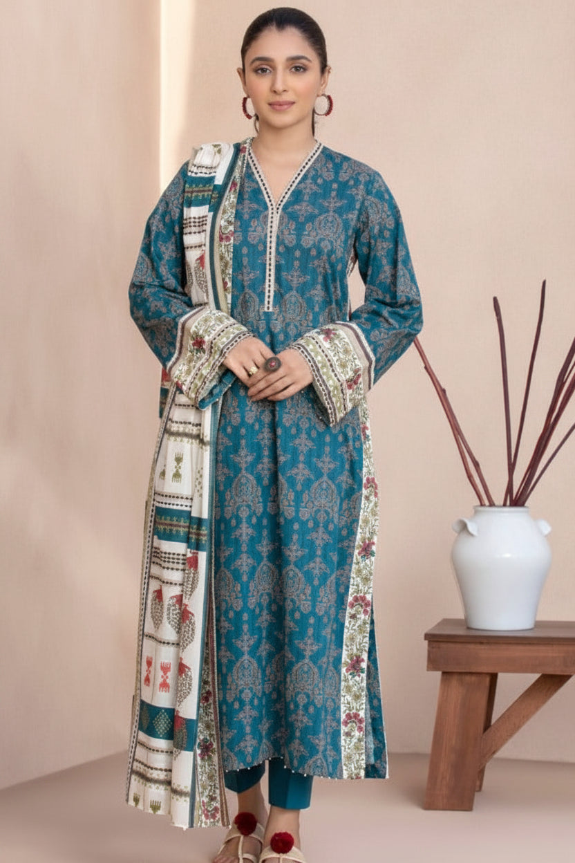 SAPPHIRE Daily Lawn Suit collection page featuring a model wearing a three-piece printed outfit: a blue kurta, matching trousers, and a patterned dupatta, with product details and a barcode on a white page.